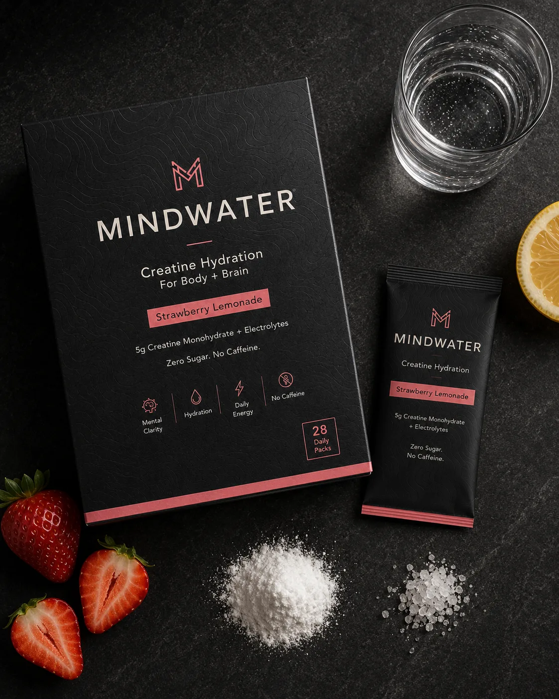 Overhead still life of creatine powder, electrolyte crystals, strawberry halves, lemon, water, and a MINDWATER daily pack on dark stone